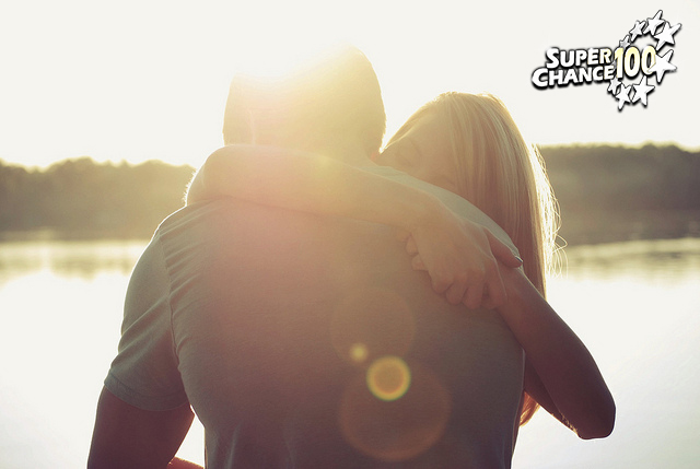 Photographie d'un couple s’enlaçant devant un coucher de soleil.